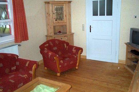 Ansicht des Wohnzimmers mit Sessel Couch und Fernseher